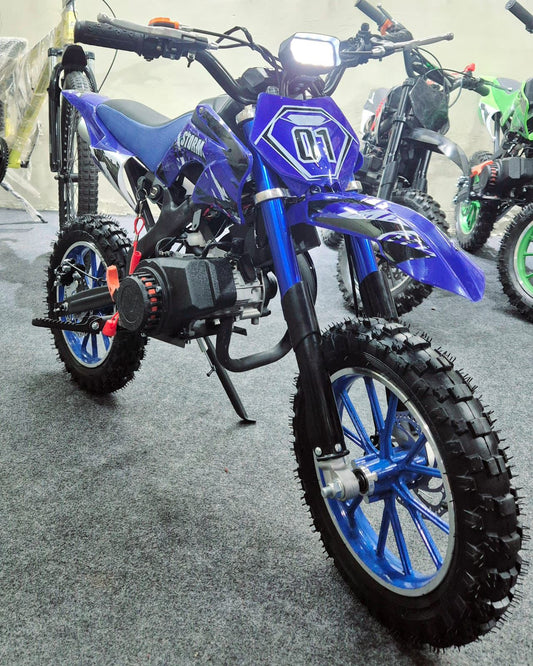 Blue children's dirt bike with visible branding on a gray floor.